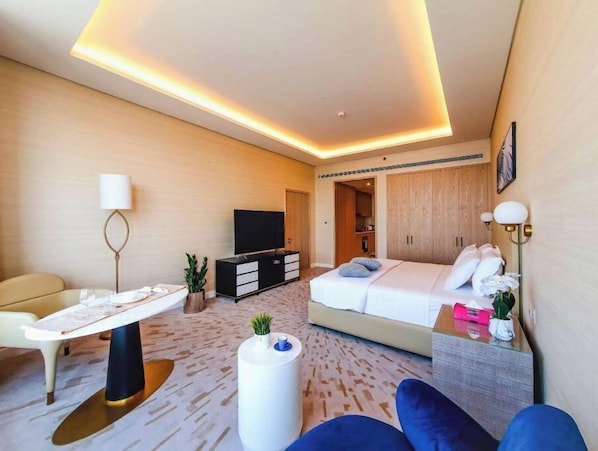 Une chambre d’hôtel moderne équipée d’un lit, d’un bureau avec une chaise, d’une télévision et d’une armoire.