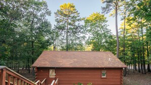 A rustic log cabin with a wooden deck and a small garden area. - Cabin I at Safe Harbor Brady Mountain on Lake Ouachita! (Royal)