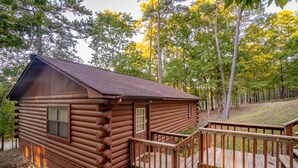 A log cabin with a wooden deck and a small porch. - Cabin I at Safe Harbor Brady Mountain on Lake Ouachita! (Royal)