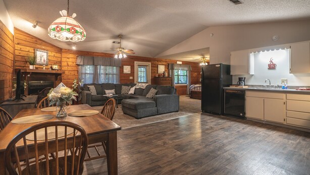 A cozy cabin-style interior with a dining area, living room, and kitchen. - Cabin I at Safe Harbor Brady Mountain on Lake Ouachita! (Royal)
