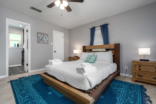 A spacious bedroom with a large bed, a ceiling fan, and a wooden headboard. - Relaxing house with Hot Tub and Private Pool (Killeen)