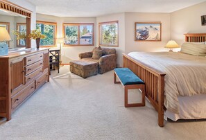 Ein Schlafzimmer mit einem Bett, einer Bank, einem Sessel, einem Schminktisch und einem Schreibtisch.
