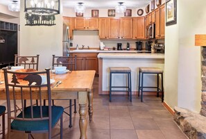 A kitchen with wooden cabinets, a dining table with chairs, and a bar area. - Spacious Breck Hideaway. Hot Tub. On Town Bus. (Breckenridge)