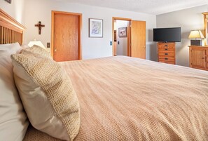 A bedroom with a large bed, wooden doors, a television, and a dresser. - Spacious Breck Hideaway. Hot Tub. On Town Bus. (Breckenridge)