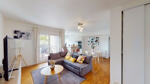 Ein modernes Wohnzimmer mit grauem Sofa, einem kleinen runden Tisch und einem Fernseher.