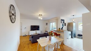 Eine moderne Wohnung mit Wohnzimmer, Essbereich, Küche und einem großen Fenster.