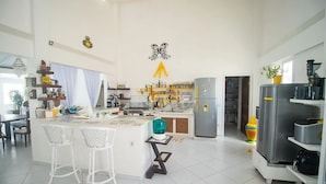 Een ruime keuken met een centraal eiland, barkrukken en moderne apparatuur.