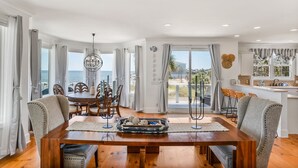 Ein Essbereich mit Holztisch, Stühlen und Blick aufs Meer.