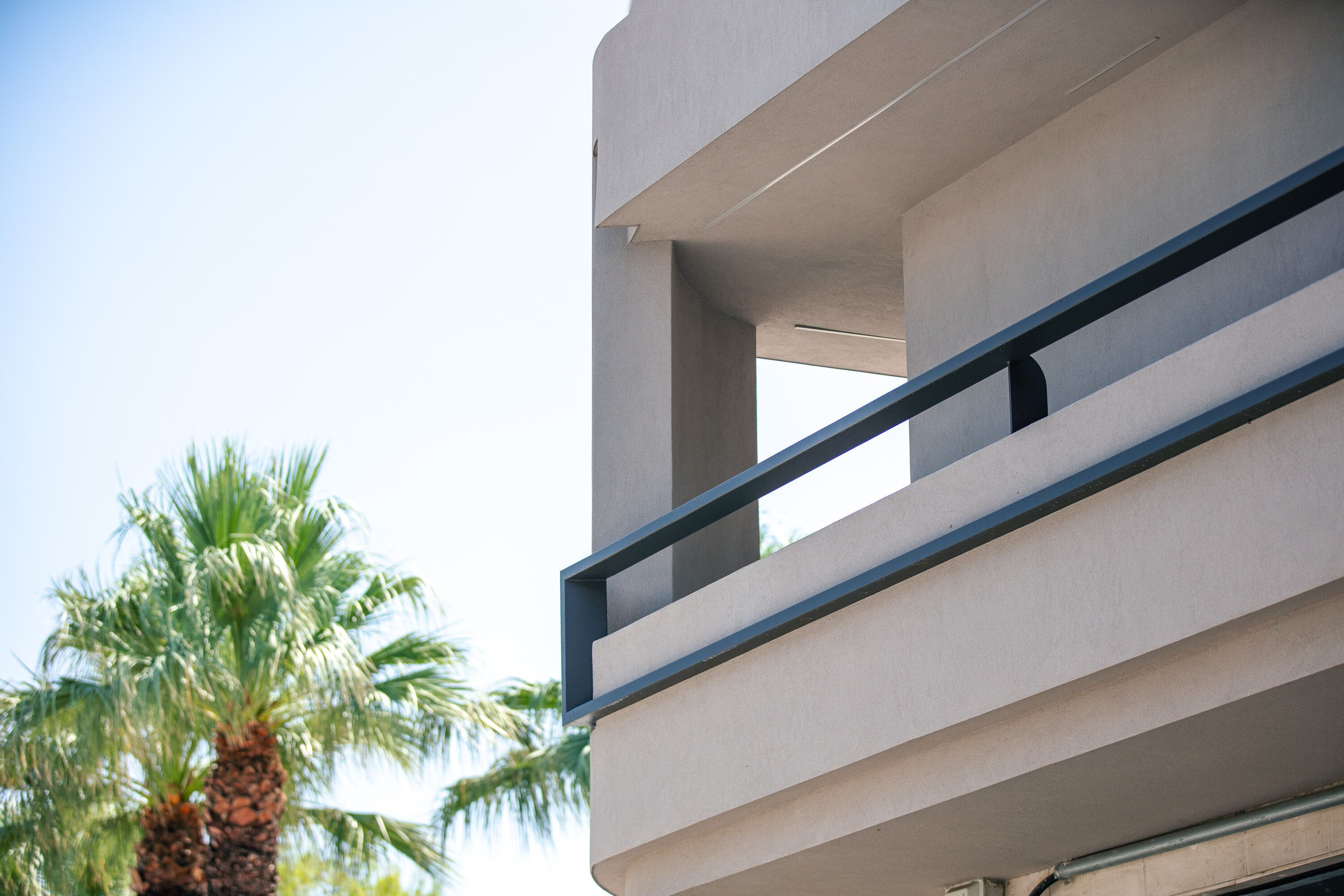 Un edificio moderno con un balcone e una palma sullo sfondo.