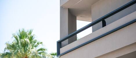 Un edificio moderno con un balcone e una palma sullo sfondo.