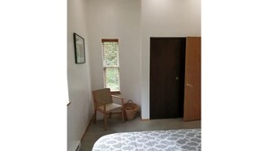 A bedroom with a bed, a chair, a window, and a door. - Modern 2 bedroom. Minutes airport & ferry (Juneau)
