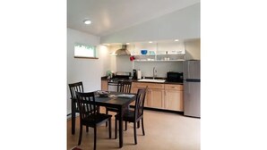 A compact kitchen with a dining table and chairs, a stove, a sink, and a refrigerator. - Modern 2 bedroom. Minutes airport & ferry (Juneau)
