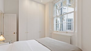 Ein Schlafzimmer mit Bett, Fenster, Heizkörper und Tür.