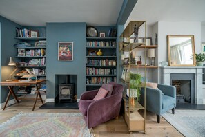 Ein Wohnzimmer mit Kamin, Bücherregalen, einer Couch und einem Couchtisch.