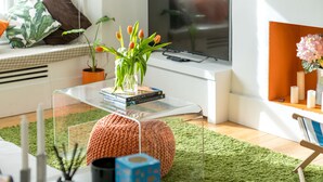 A modern living room with a glass coffee table, a potted plant, a television, and a cozy seating area. - JOIVY Captivating 2-Bed Flat In Shepherd'S Bush (London)