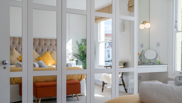 A bedroom with a large bed, a nightstand, a mirror, and a window with a view of the outside. - JOIVY Captivating 2-Bed Flat In Shepherd'S Bush (London)