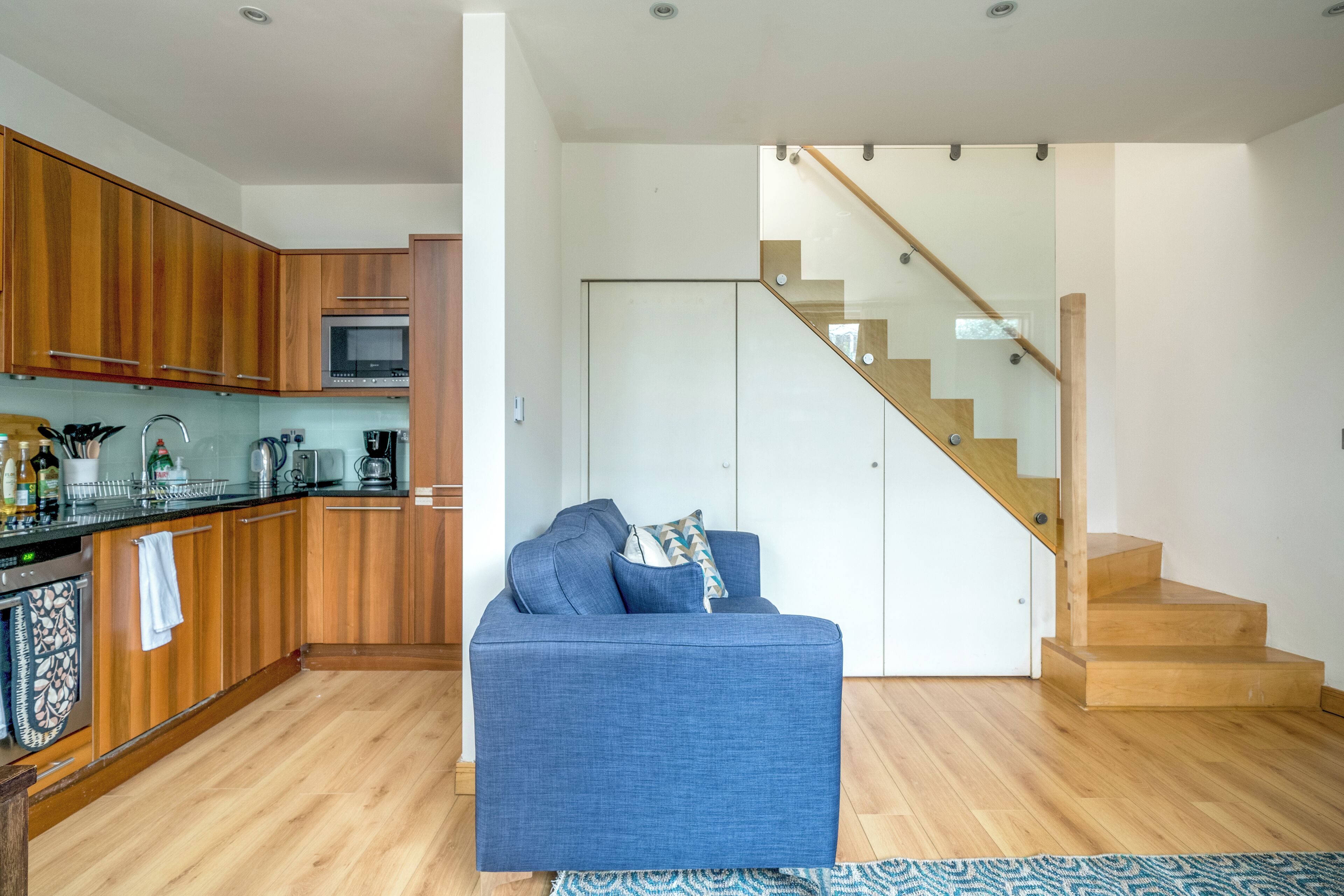 A modern kitchen with wooden cabinets, a built-in microwave, and a stainless steel sink.
