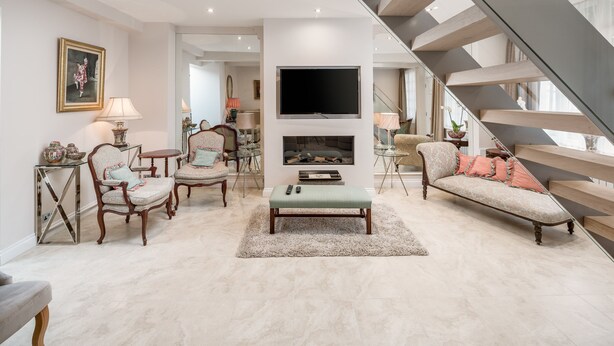 Ein geräumiges Wohnzimmer mit moderner Treppe, Kamin und bequemen Sitzgelegenheiten.