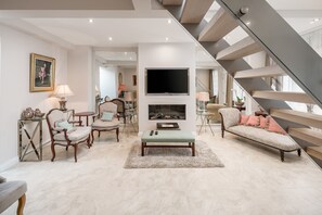 A spacious living room with a modern staircase, a fireplace, and comfortable seating. - JOIVY Elegant house with rooftop terrace (London)