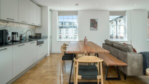 Una cocina moderna con armarios blancos, una mesa de comedor de madera y un sofá.