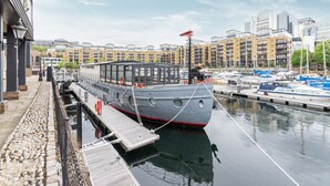 Een boot afgemeerd in een jachthaven, met een stadsgezicht op de achtergrond.