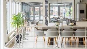 Een moderne eethoek met een lange tafel, grijs gestoffeerde stoelen en een potplant.