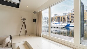 Een moderne kamer met een groot raam dat uitkijkt over een jachthaven, een statief en een bank.
