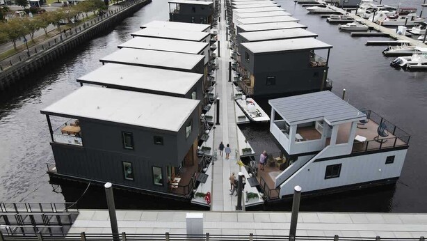 A waterfront property with multiple docked boats, a pedestrian walkway, and a view of the water.