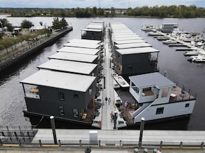 A waterfront property with multiple docked boats, a pedestrian walkway, and a view of the water.