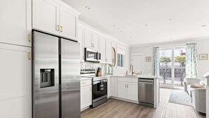 A modern kitchen with white cabinets, stainless steel appliances, and a wooden floor.