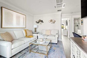 Een moderne woonkamer met een witte bank, een salontafel en decoratieve wandkunst.