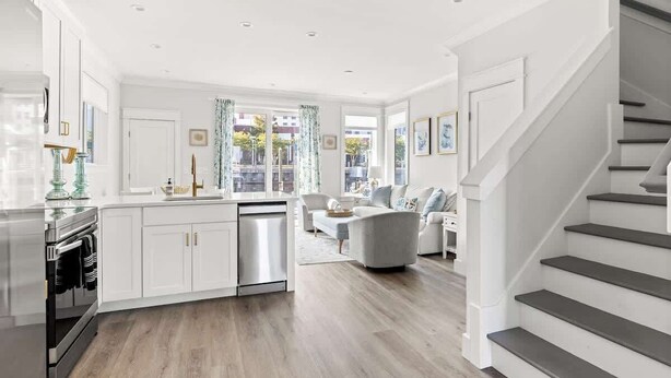 A modern kitchen with white cabinetry, a stainless steel range, and a dishwasher.