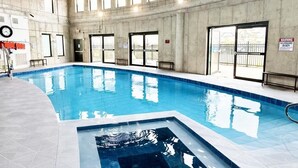 Una piscina interior con agua cristalina, rodeada de paredes y suelo de baldosas.