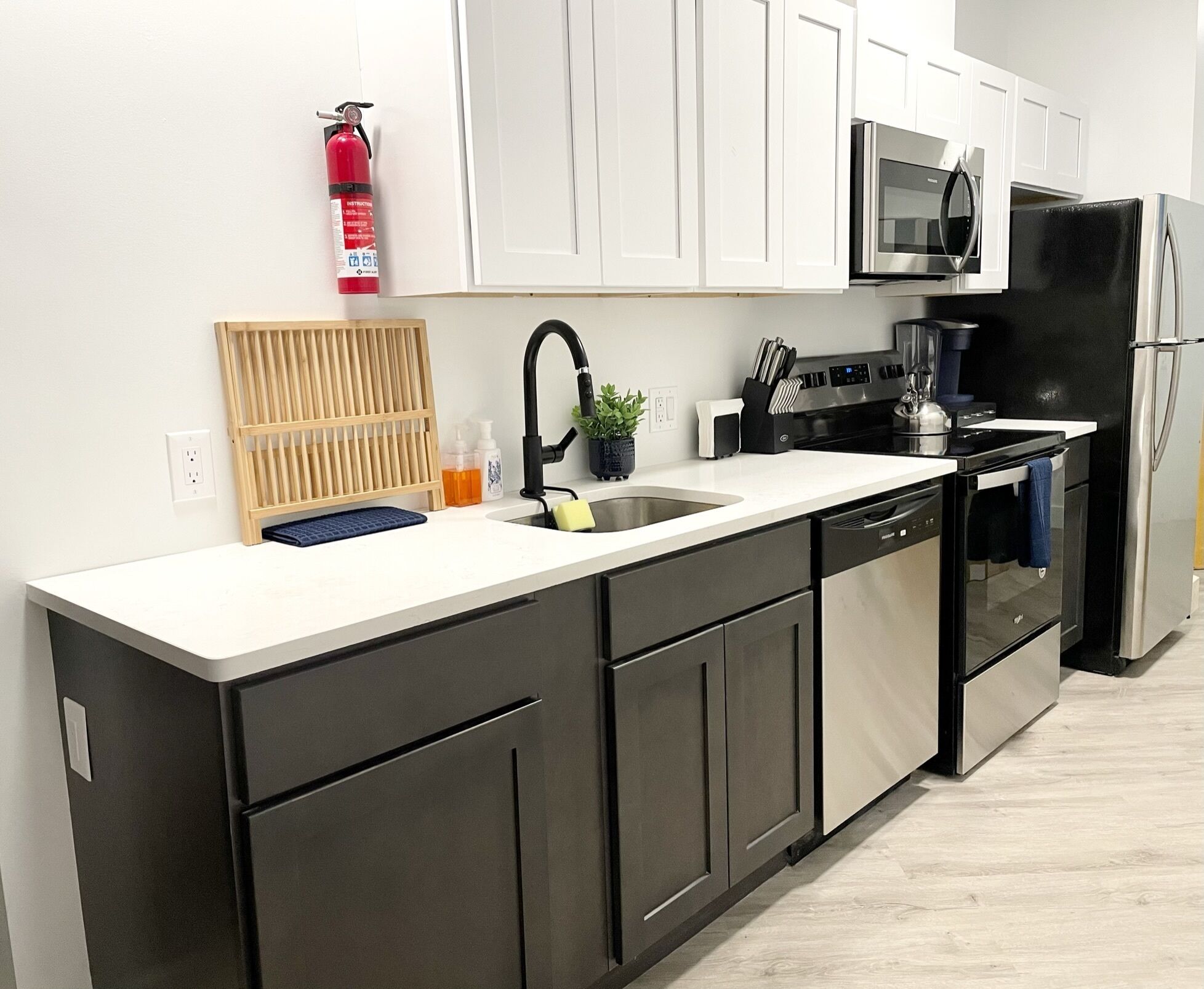 A modern kitchen with white cabinets, stainless steel appliances, a black dishwasher, and a built-in oven.