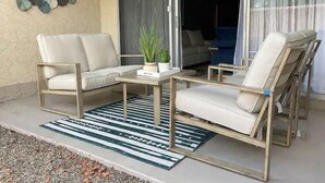 Uma área de pátio com um conjunto de sofá, uma mesinha e um vaso de planta.