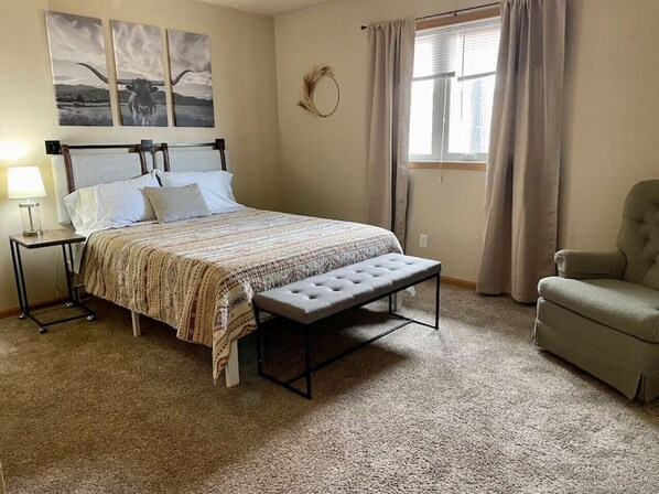 A bedroom with a bed, bench, chair, and artwork on the wall. - Spacious 2 BDRM/sleeps 6 (Laramie)