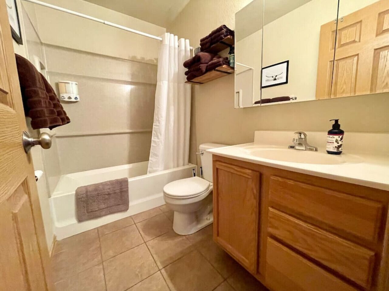 A bathroom with a bathtub, toilet, and wooden cabinets.