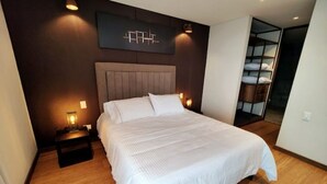 Ein modernes Schlafzimmer mit einem großen Bett, einem Nachttisch, einer Wandleuchte und einer eingebauten Regaleinheit.