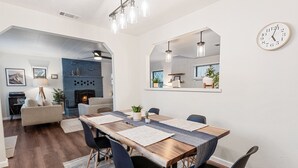A modern dining area with a wooden table, black chairs, and a mirror above. - Badger Den - Walk to Village, Walk to Shops, Modern, Fenced Yard (Big Bear Lake)