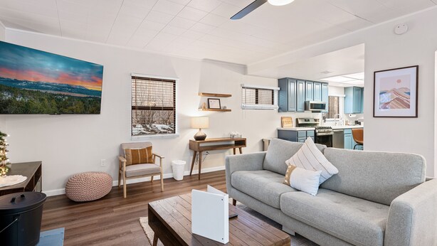 A modern living room with a grey sofa, wooden coffee table, and a dining area with a table and chairs. - Badger Den - Walk to Village, Walk to Shops, Modern, Fenced Yard (Big Bear Lake)
