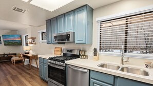 A modern kitchen with blue cabinets, stainless steel appliances, and a wooden floor. - Badger Den - Walk to Village, Walk to Shops, Modern, Fenced Yard (Big Bear Lake)
