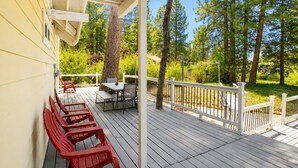 A wooden deck with outdoor furniture, a white railing, and a view of a forested area. - Jaybird Lodge - Walk to Lake & Village, Fireplace, AC (Big Bear Lake)