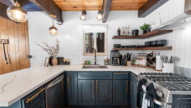 A modern kitchen with dark blue cabinets, a stainless steel stove, and a white marble countertop.