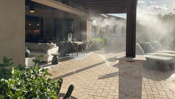 Un patio al aire libre cubierto con una mesa, sillas, un sofá blanco y una planta de cactus.
