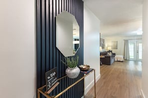 A hallway with a dark blue wall, a large mirror, a potted plant, and a sign with text.