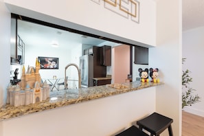 A kitchen with a granite countertop, a stainless steel refrigerator, and a black bench. - 8 Min to Disney !! Private Pool !! (Kissimmee)