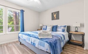 Un dormitorio con una cama grande, dos mesitas de noche, una ventana con cortinas y un cuadro colgado en la pared.