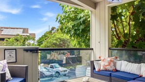 Ein Balkon mit Korbmöbeln, einer Glastür und Blick auf einen Parkplatz.