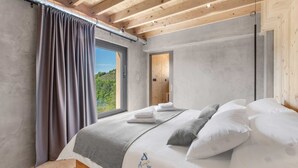 A bedroom with a large bed, a view of greenery outside, and wooden ceiling beams. - Luxurious 4-BR villa for up to 8 with pool and spa (Golubići)