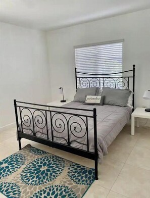 Cozy retreat with a single bed, bedside table, and lamp, set against a serene backdrop.